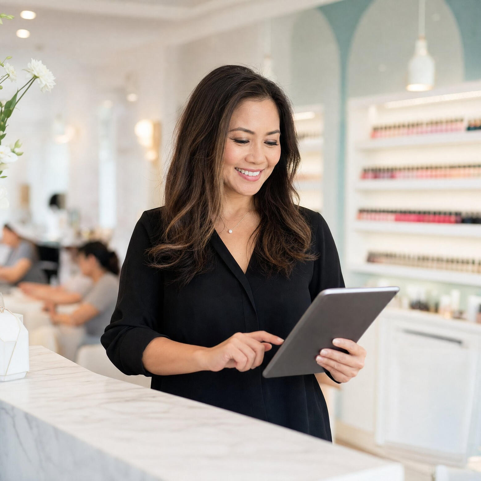 Nail salon owner at the front desk reviewing her price menu on a tablet